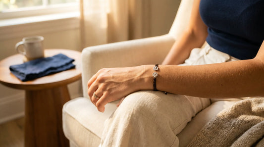 A woman's wrist wearing a small paw print memorial bracelet in soft afternoon light