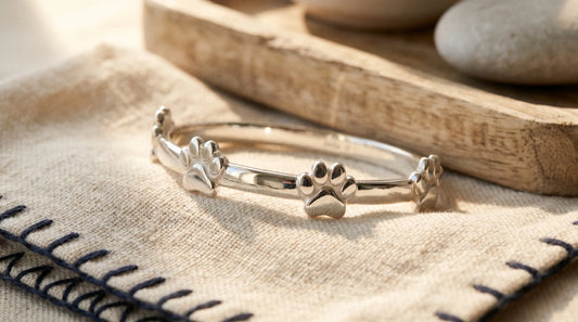 Close-up of a polished silver paw-print bracelet showing pristine untarnished surface