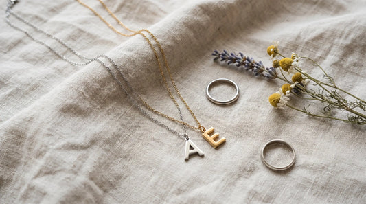 Two delicate matching couples necklaces with initial pendants on natural linen in soft daylight