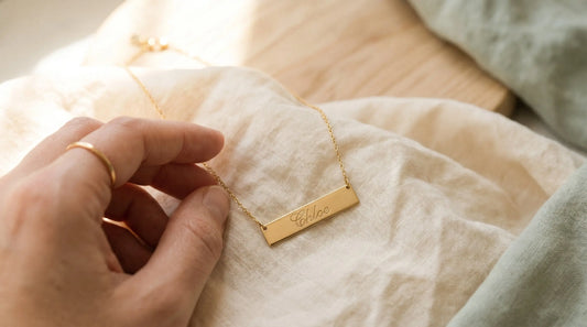 Sideways personalized name necklace in gold-plated stainless steel on cream linen