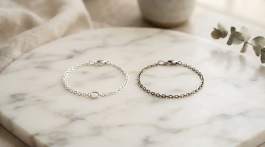 Two silver bracelets side by side on marble — 316L surgical grade vs 304 stainless steel comparison