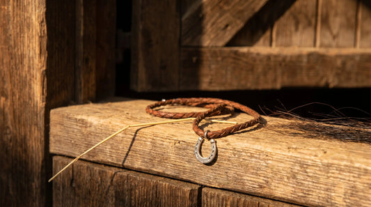 Engraved horseshoe pendant on weathered saddle leather in golden hour light