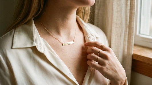Sideways gold-plated name necklace lying flat across collarbone — modern minimalist style