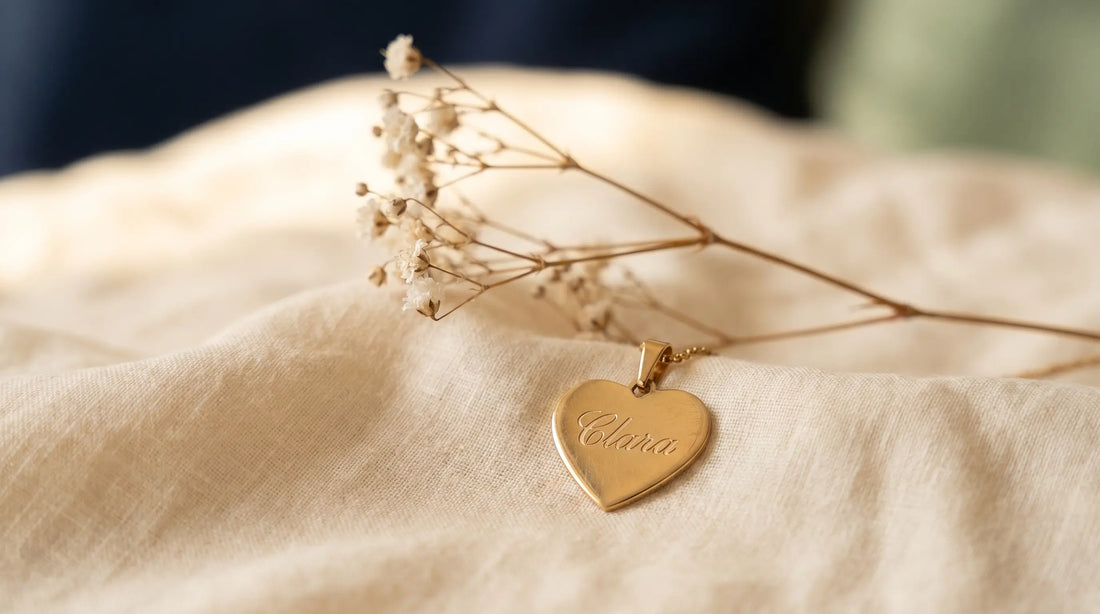 Engraved heart memorial necklace on cream linen with sprig of baby's breath — gentle tribute