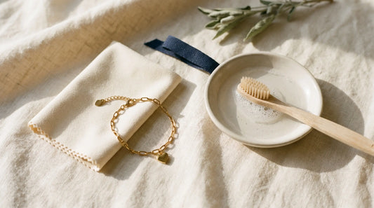 Stainless steel jewelry care arrangement — bracelet, microfiber cloth, soapy water, soft brush