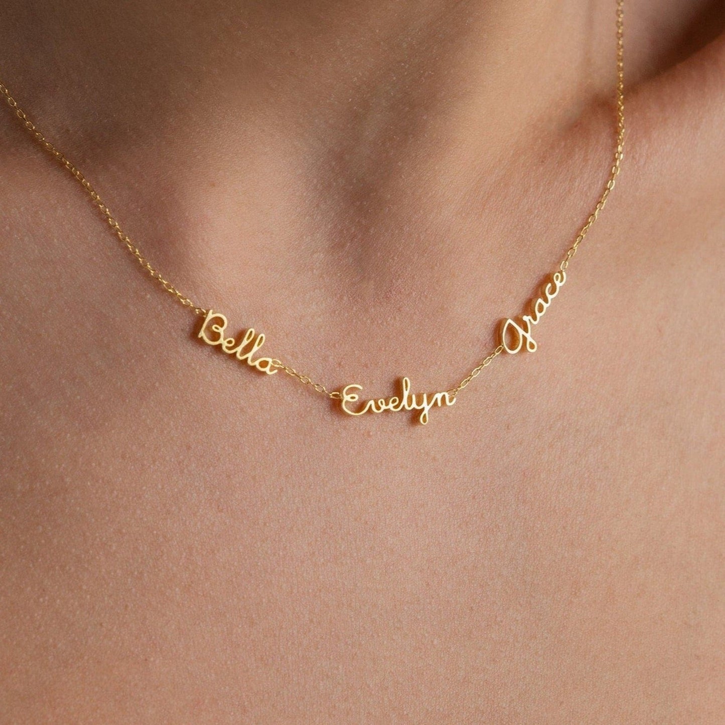 The Dainty Tiny Multiple Name Necklace features three names—Bella, Evelyn, and Grace—in delicate cursive, offering a personalized and elegant accessory for a unique, meaningful touch.